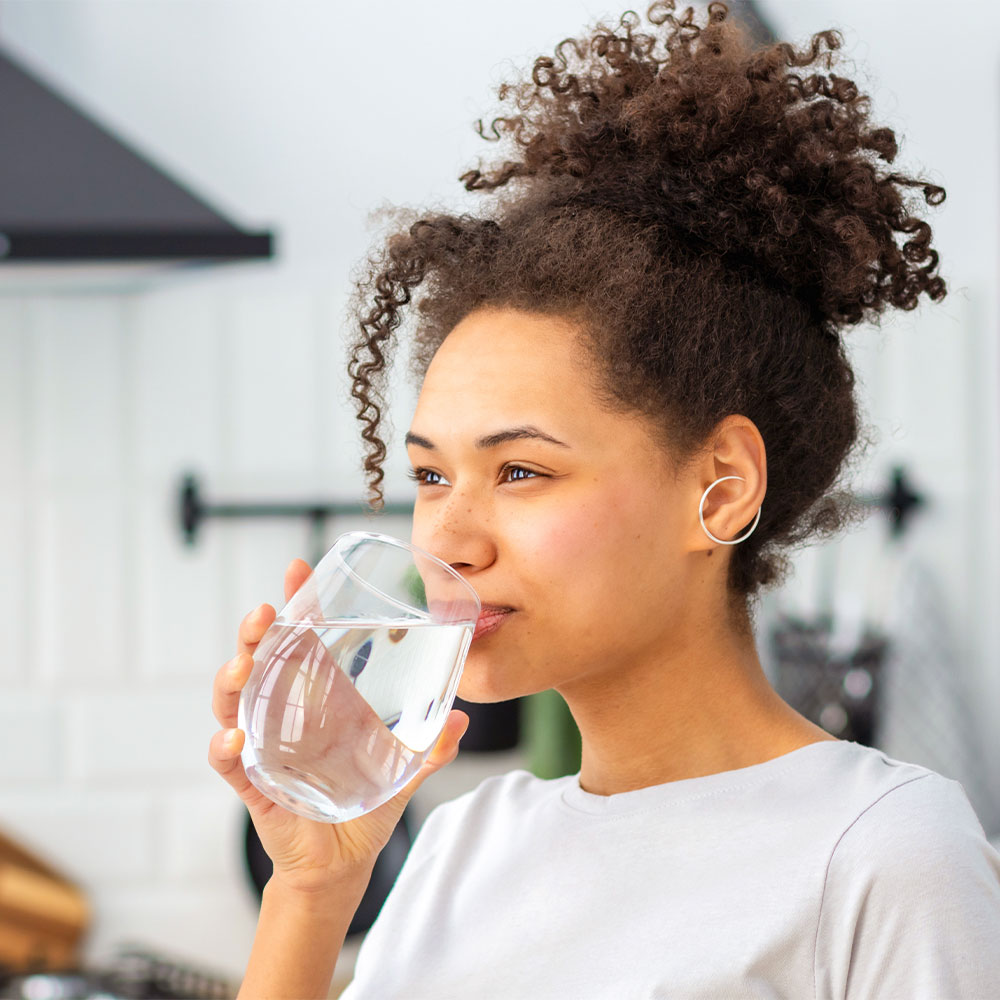 Frau trinkt Wasser aus einem Glas