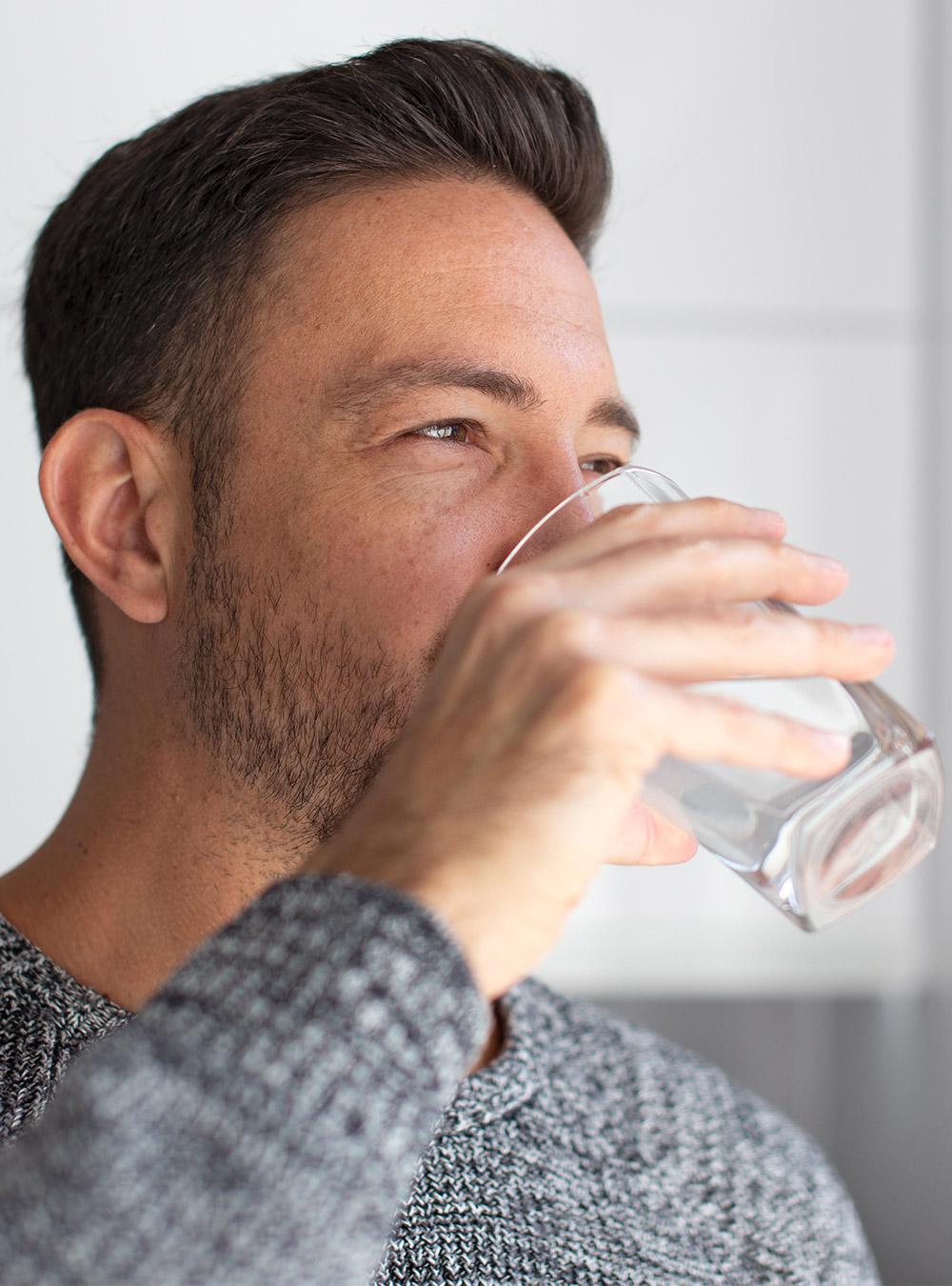Mann trinkt Wasser aus einem Glas